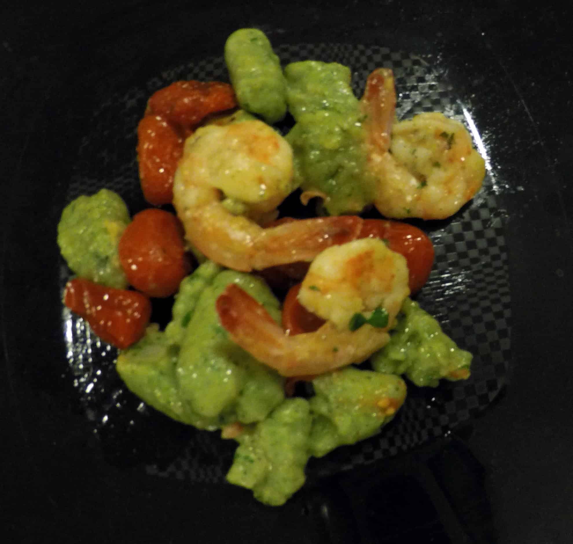 Gnocchi verdi con gamberi e pomodorini Piatto di gnocchi verdi con gamberi e pomodorini servito durante un corso di cucina.